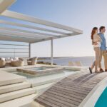 6 Modern Wellness Trends for Upscale Homes A young man and woman standing side by side on a bridge above a luxurious pool overlooking the ocean.