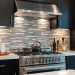Top 4 Advantages of Stainless Steel Appliances A modern kitchen with a stainless steel gas range and hood. The countertops are white and the cabinets are black.