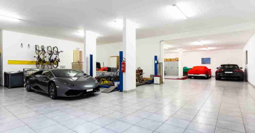Three cars parked in a tiled garage with white walls, a four-post auto lift, hanging bikes, and storage cabinets.