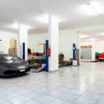 5 Luxury Garage Design Tips for the Perfect Showroom Three cars parked in a tiled garage with white walls, a four-post auto lift, hanging bikes, and storage cabinets.