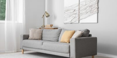 The interior of a luxury home with a gray sofa. Hanging on the wall are two pieces of textured wall art.