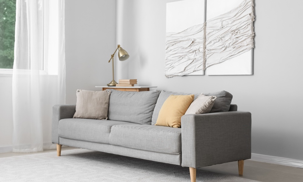 The interior of a luxury home with a gray sofa. Hanging on the wall are two pieces of textured wall art.